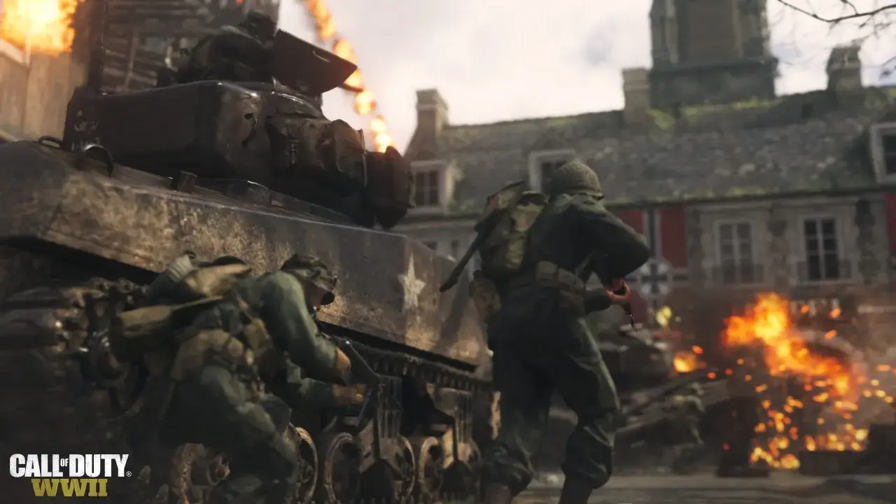 Żołnierze w akcji przy czołgu, płomienie i wybuchy. Scena z gry Call of Duty: WWII.