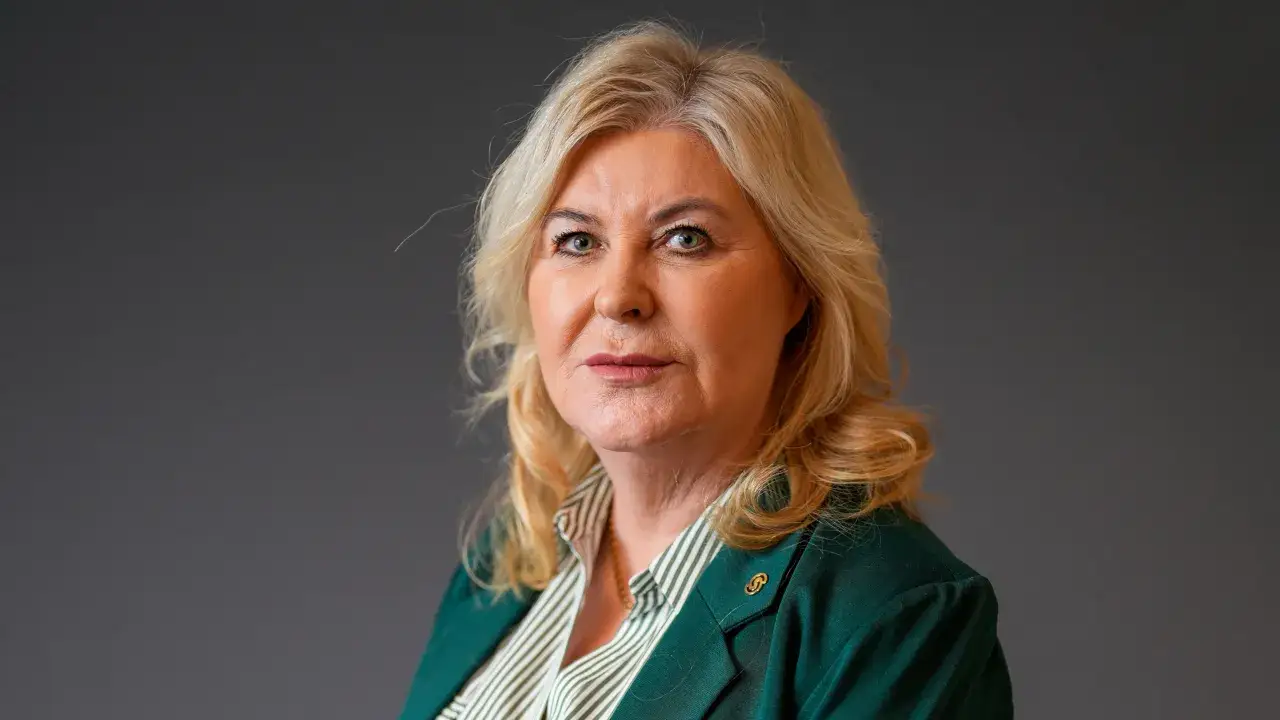 Helya Riazat, en kvinna med blont h&aring;r och gr&ouml;n kavaj, ser rakt in i kameran.