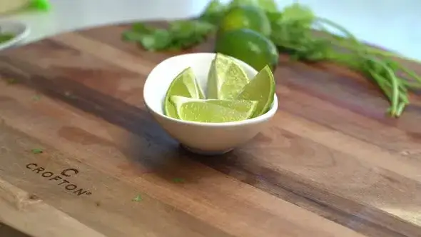 Frische Limetten und Limettenh&auml;lften auf einem Schneidebrett