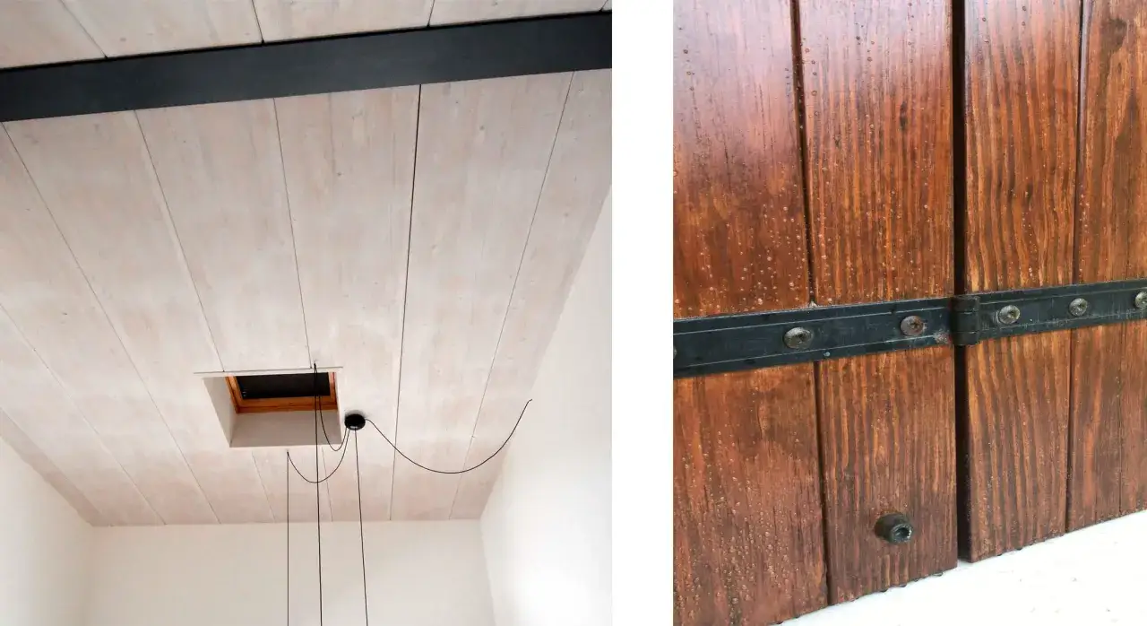 Soffitto in legno sbiancato con trave nera e botola. Porta in legno scuro con cerniere metalliche, il **mordente significato** è la profondità del colore.