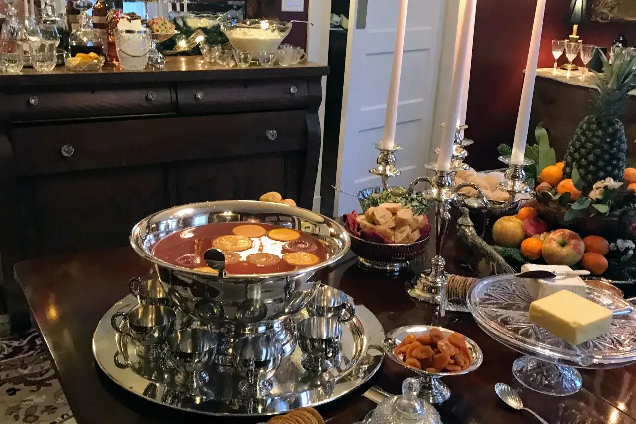 Un grand bol de punch aux fruits, garni de rondelles d'orange, prêt pour une recette de punch sans alcool pour 30 personnes. Fruits, biscuits et bougies sur la table.