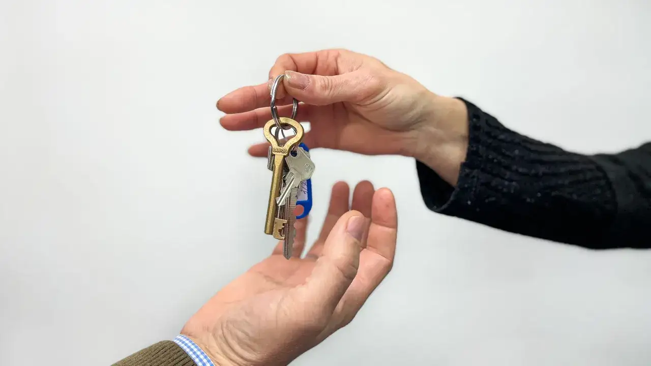 Manos intercambiando llaves, simbolizando un acuerdo de subarriendo de vivienda.