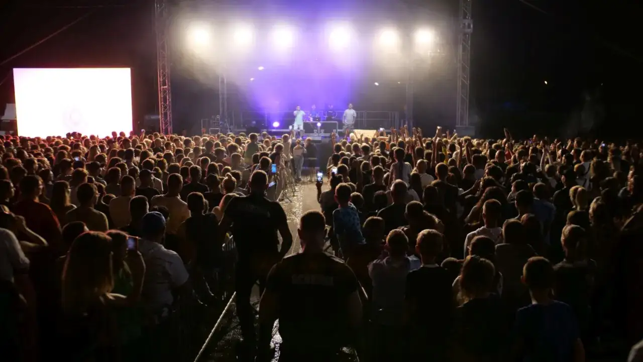Tłum ludzi na koncercie Kubanczyka. Na scenie artyści, przed nimi rozświetlona publiczność.