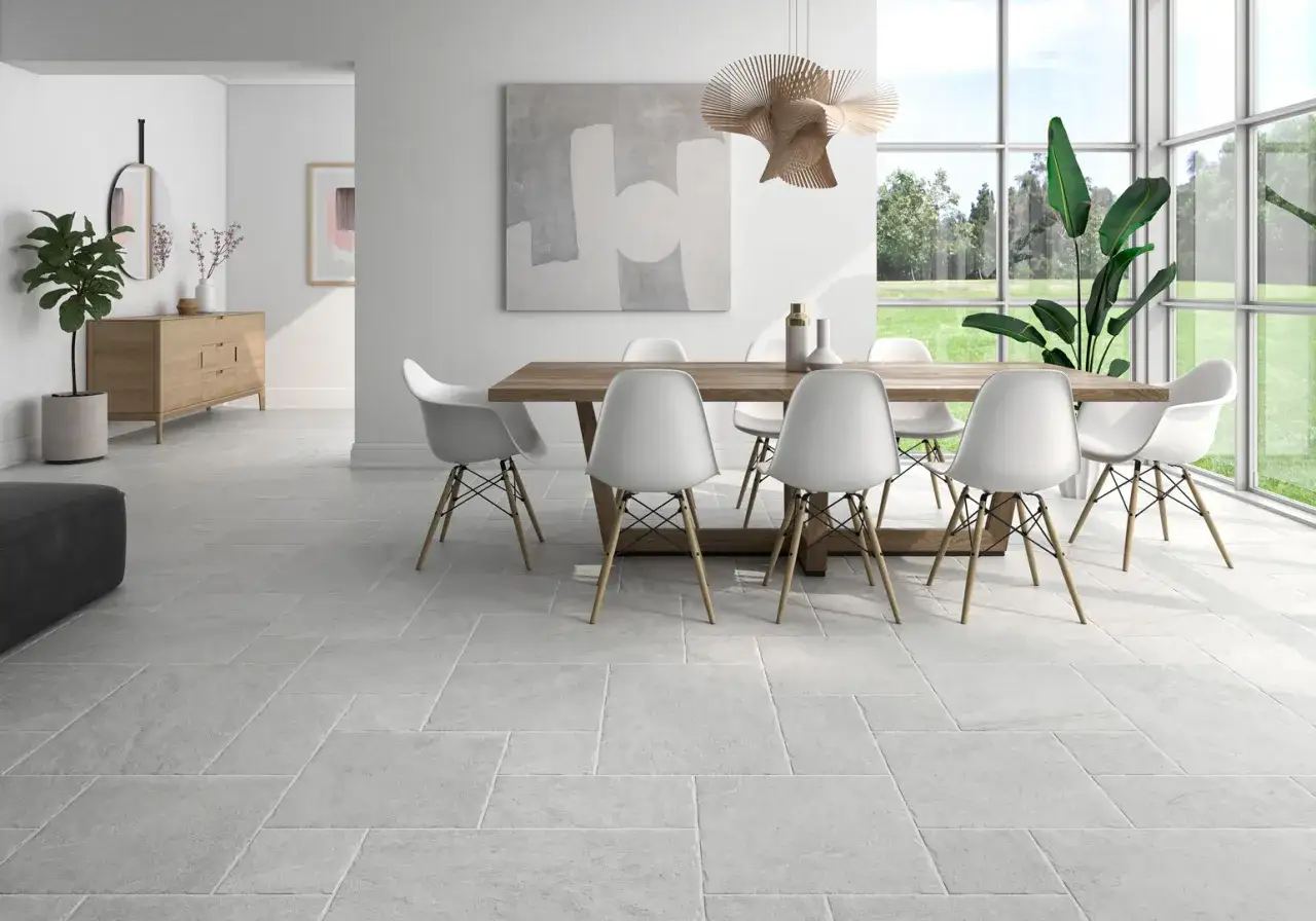 Comedor con sillas blancas y mesa de madera, todo en un estilo minimalista. Grandes ventanales dejan entrar luz natural.