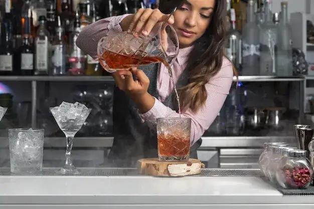 kobieta barmanka przygotowująca koktajl w eleganckim barze