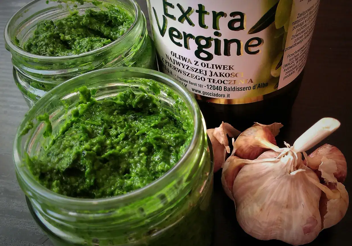 Pesto z jarmużu do słoika, obok czosnek i butelka oliwy Extra Vergine. Domowe, zdrowe i pyszne!