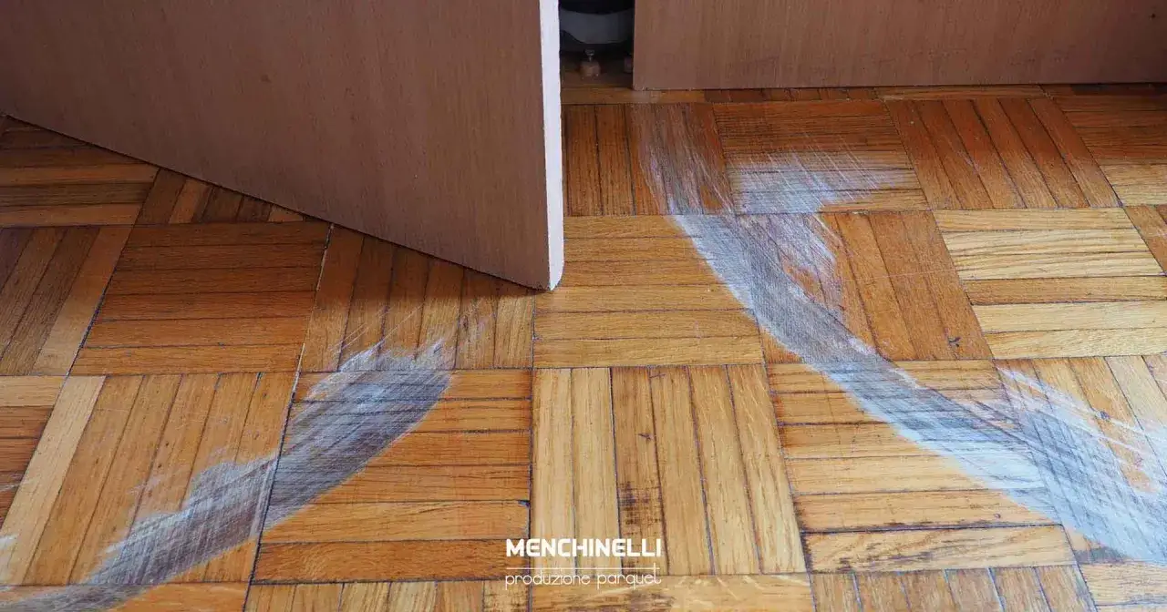 Parquet rovinato da graffi bianchi, necessita di riparazione.