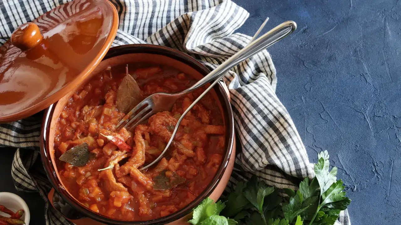Trippa ricetta napoletana in terracotta, con forchetta e peperoncino. Un piatto fumante pronto da gustare.