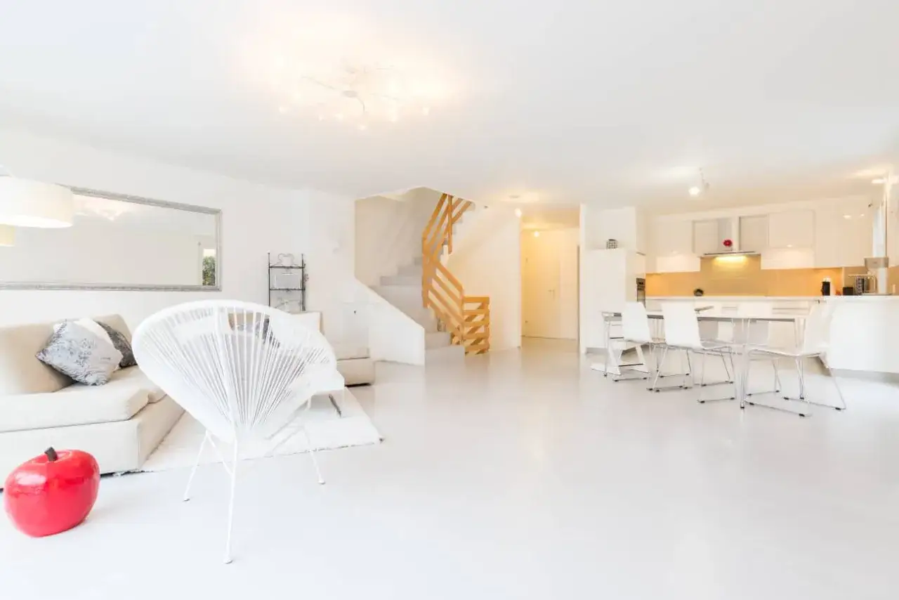 Salon et cuisine modernes, sol blanc lumineux. Le prix du béton ciré au m2 est un investissement pour ce style épuré.