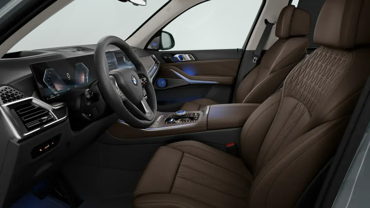 Interni lussuosi del **BMW X5 2026** con sedili in pelle marrone, cruscotto digitale e illuminazione ambientale blu.
