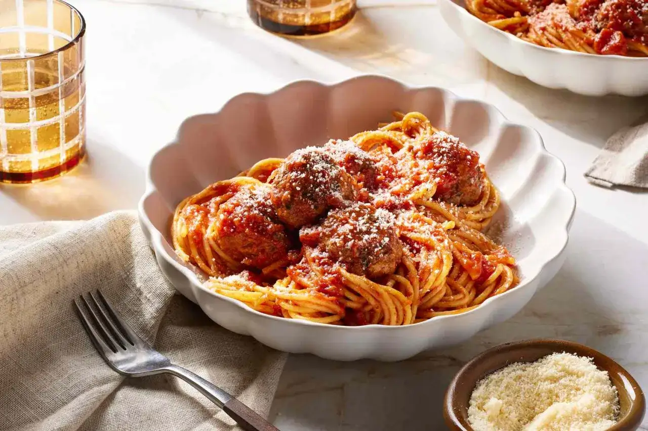 Pyszne włoskie dania z makaronem: spaghetti z klopsikami w sosie pomidorowym, posypane parmezanem.