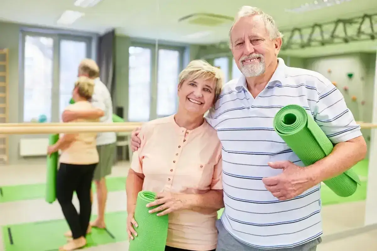 Szczęśliwa para seniorów z matami do ćwiczeń. Może to być inspiracja do wspólnego wyjazdu do sanatorium wzór za darmo.