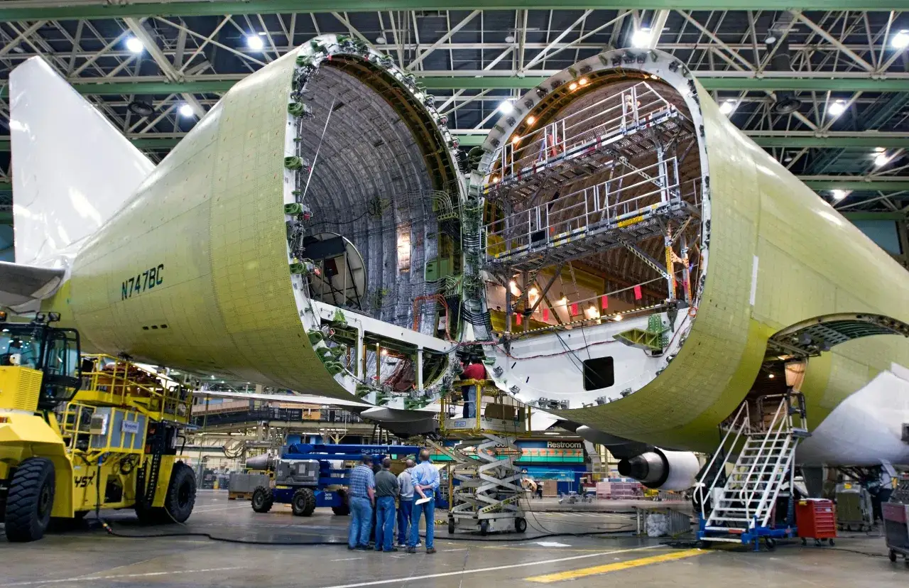 Ein Boeing 747 Dreamlifter mit geöffnetem Rumpf in einer Fabrikhalle, bereit für den Einbau von Teilen.