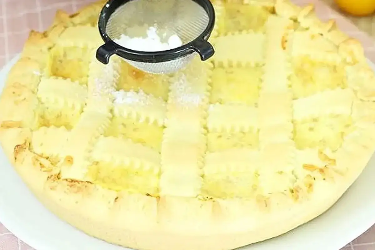 Crostata alla crema con decorazione a griglia, spolverata di zucchero a velo.