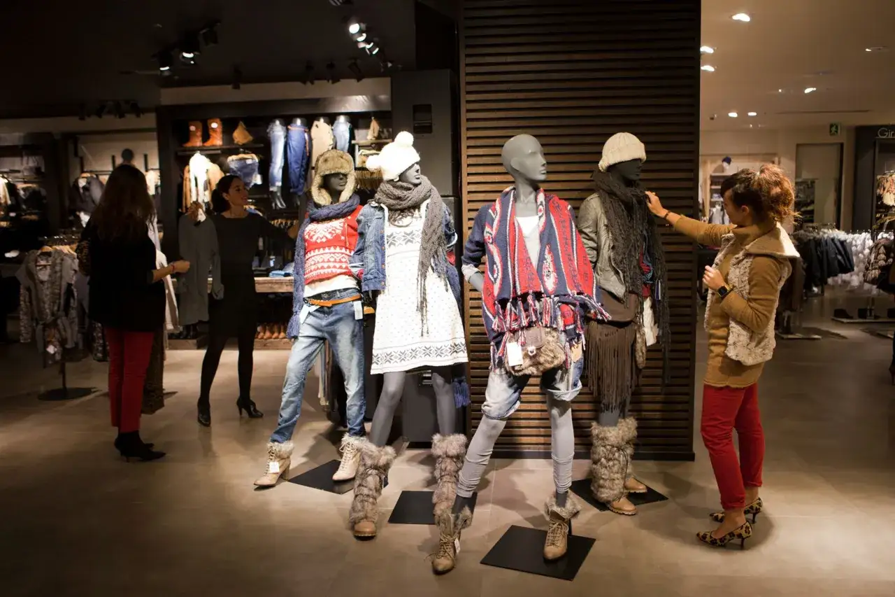 W sklepie z odzieżą marki fast fashion klientki oglądają manekiny ubrane w zimowe stylizacje.