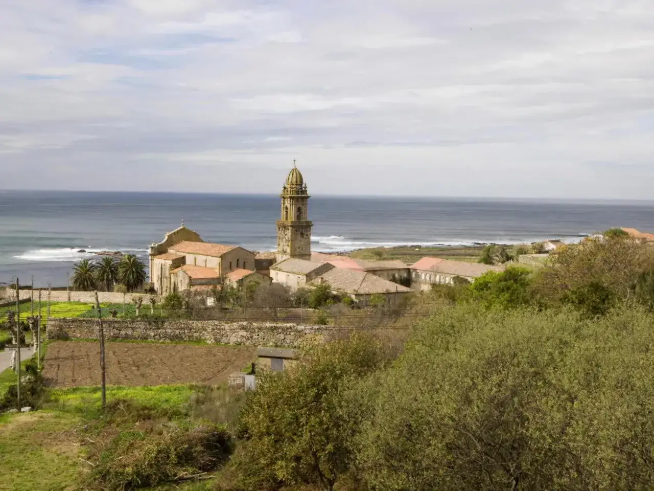 El monasterio de Oia se alza majestuoso junto al mar, con su torre campanario vigilando las olas.