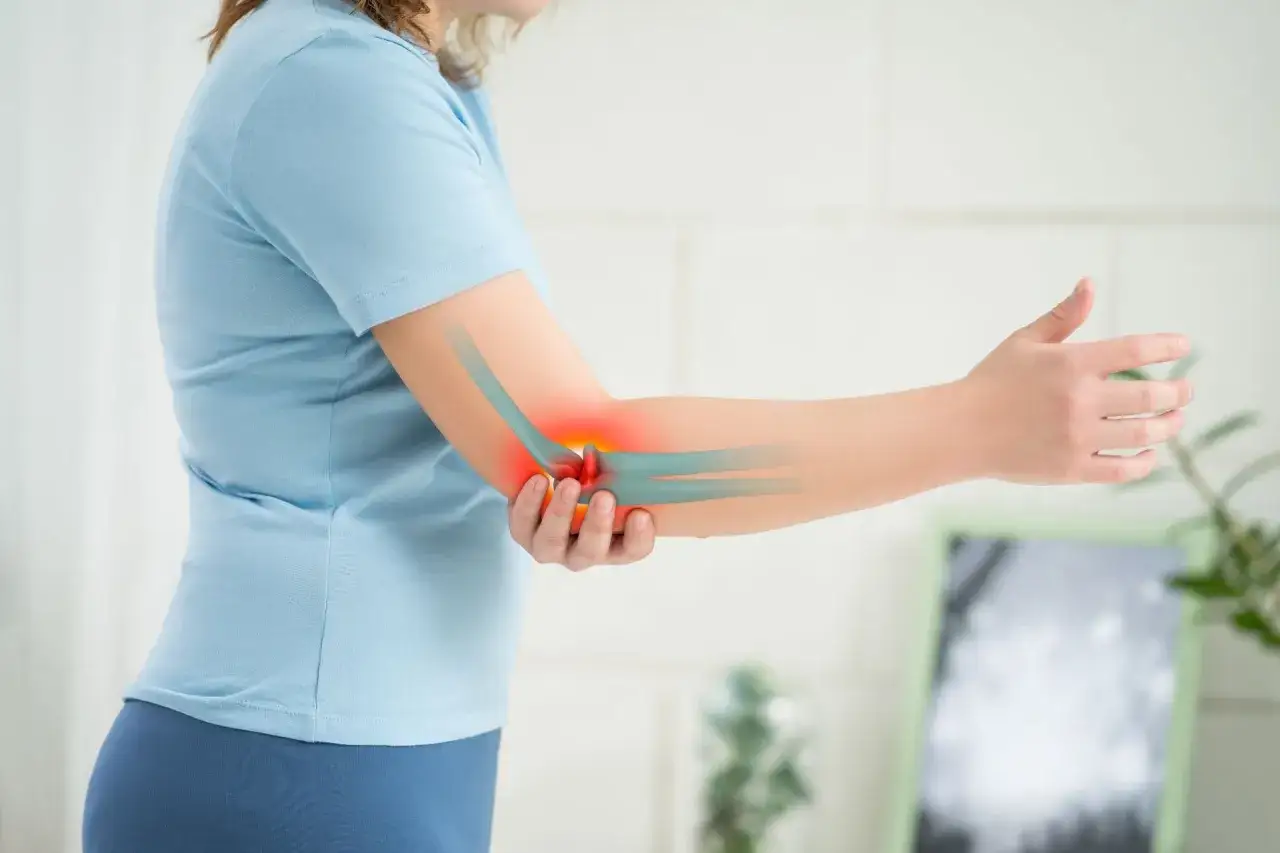 Une personne se tient le coude douloureux, o&ugrave; une zone rouge indique une inflammation. Un massage du tendon pourrait soulager cette douleur.