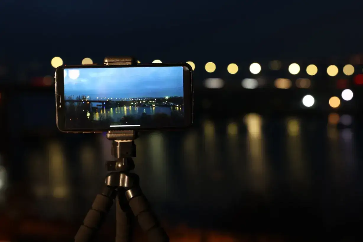 Nocny widok miasta z mostem uchwycony przez fotosmartfon na statywie.