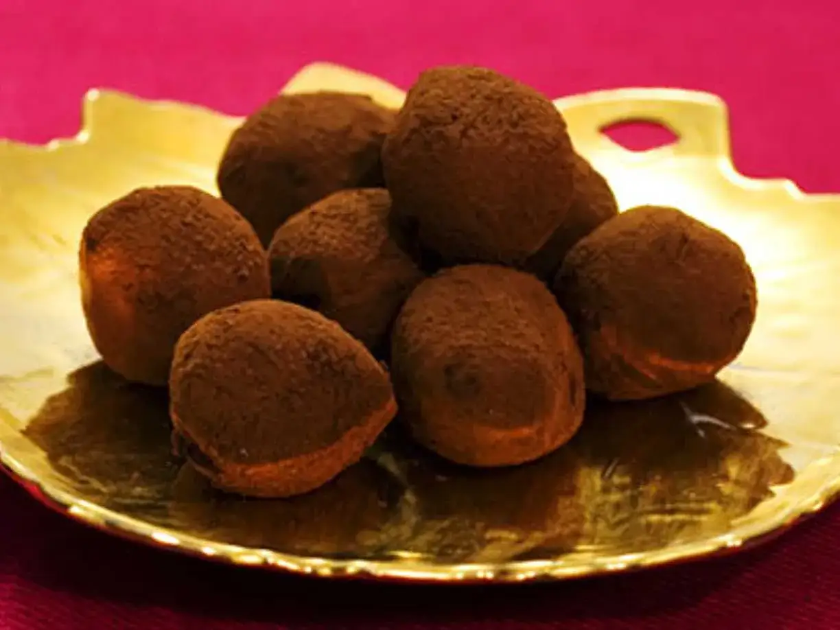 En gyllene bricka med chokladtryfflar, pudrade med kakao. Dessa l&auml;ckra trufas de chocolate ser ut att sm&auml;lta i munnen.