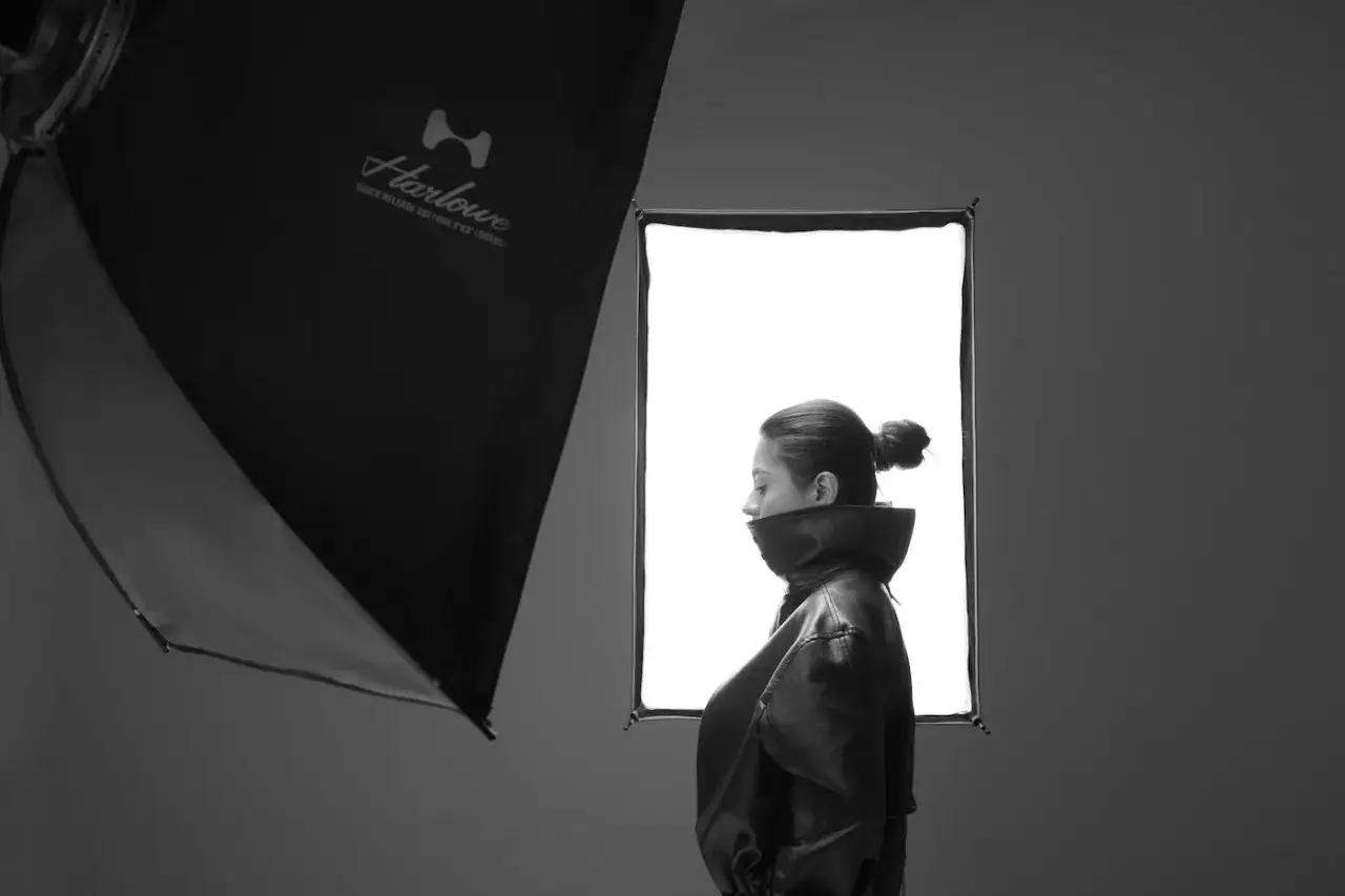 Kobieta w skórzanej kurtce, profil, w studio. Low key fotografia, miękkie światło z softboxa.
