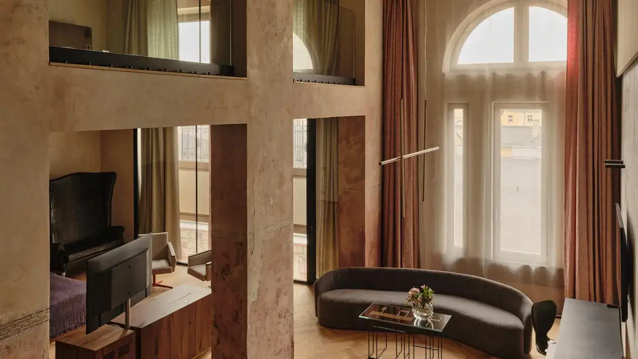 Luksusowy apartament w najdroższym hotelu w Łodzi. Wnętrze z antresolą, wygodną kanapą i designerskim fotelem.