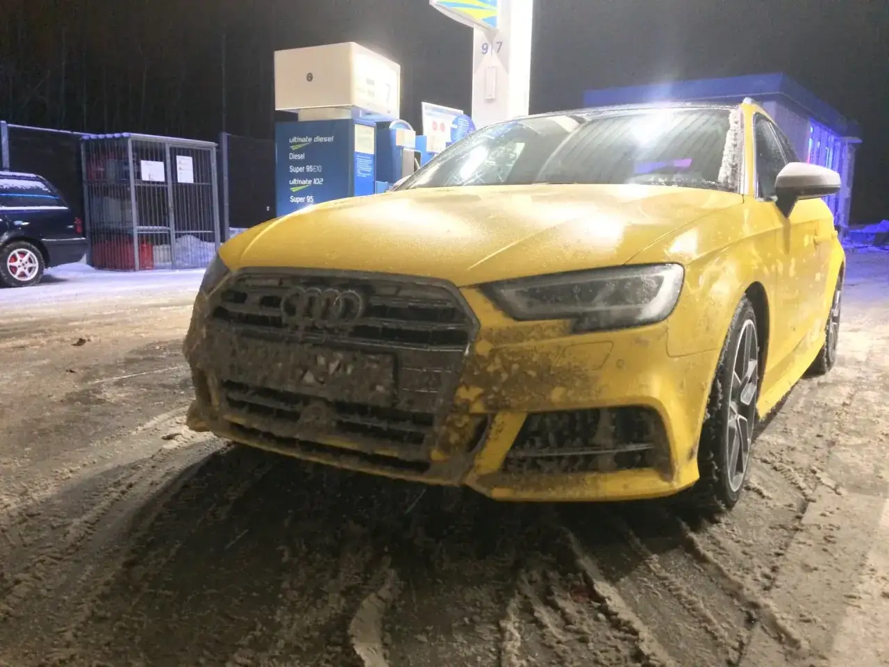 Żółte Audi mocno ubrudzone błotem i śniegiem na stacji benzynowej. Chyba czeka go mandat za brudne auto.