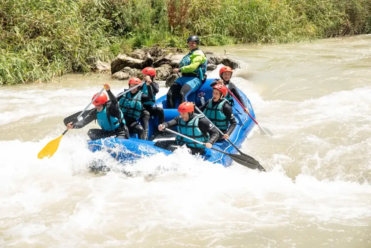 Grupo en balsa azul navegando r&aacute;pidos turbulentos, una aventura de que es rafting.