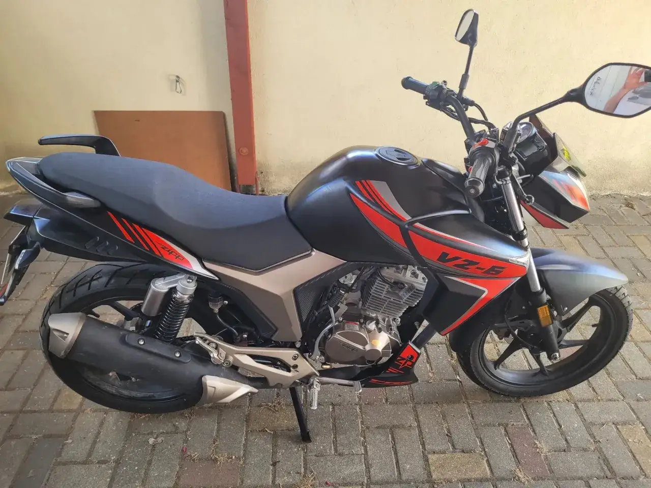Czarny motocykl Zipp Manic 125 z czerwonymi akcentami, zaparkowany na chodniku.