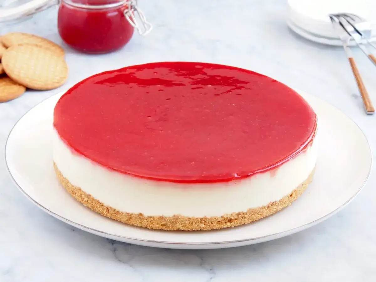Deliciosa tarta de queso con gelatina de fresa, base de galleta y un toque de mermelada.