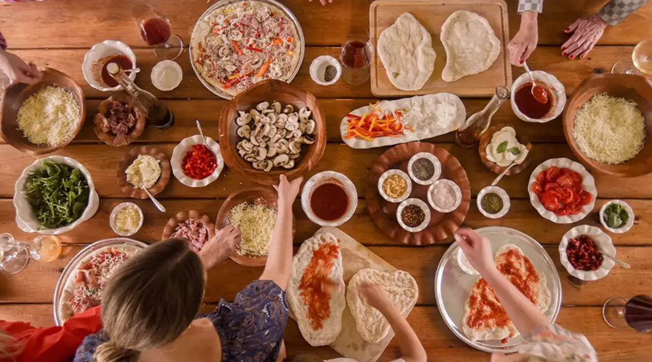 Une joyeuse pendaison de cr&eacute;maill&egrave;re avec une table garnie d'ingr&eacute;dients pour faire des pizzas. Une tradition conviviale pour c&eacute;l&eacute;brer un nouveau d&eacute;part.