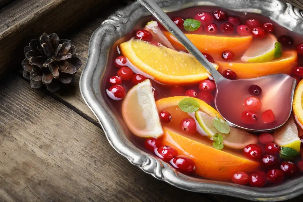 Szybki poncz alkoholowy z pomarańczą, limonką i żurawiną w metalowej misie, gotowy do podania.