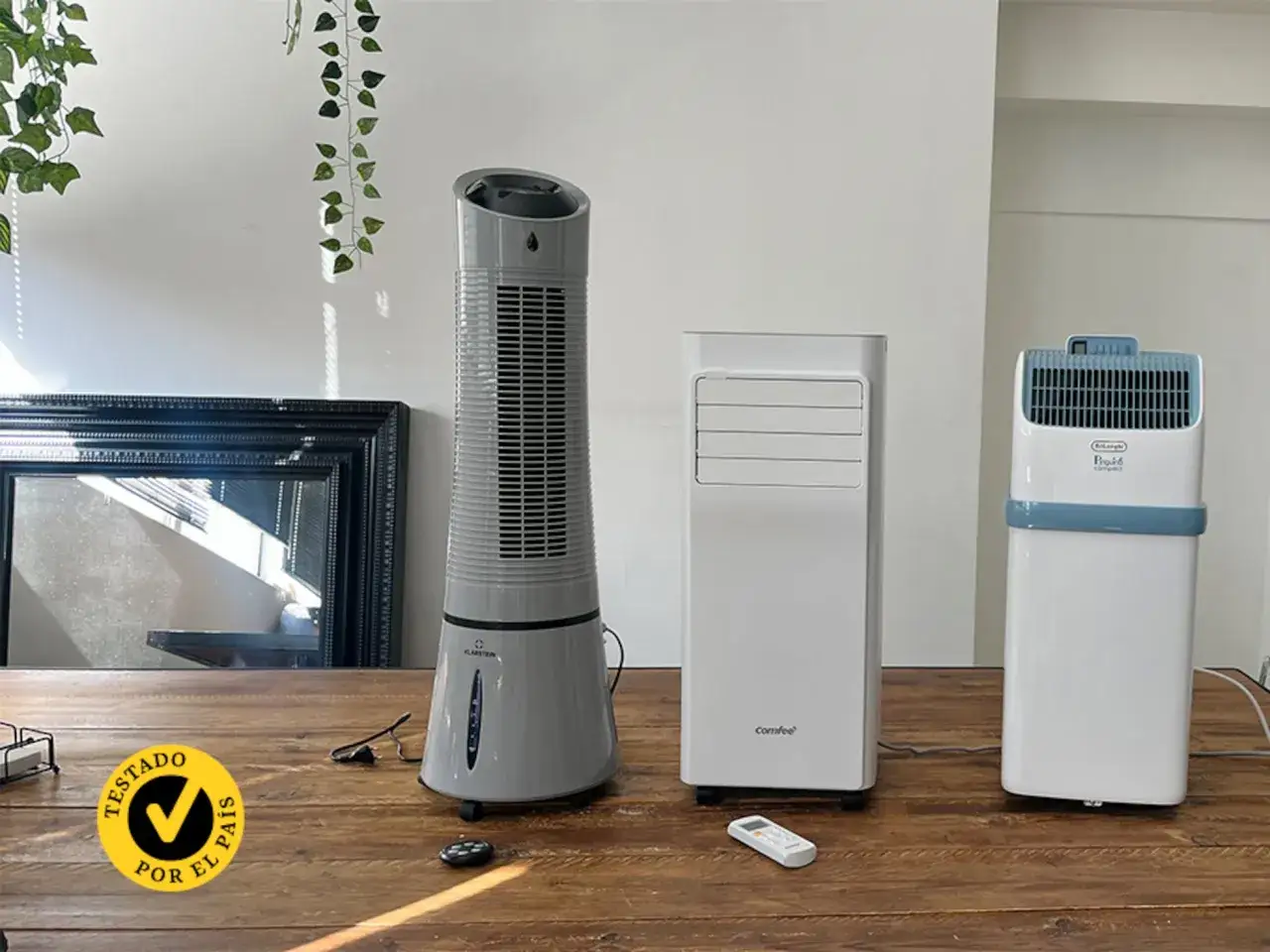 Tres aparatos de climatización: un ventilador de torre gris, un climatizador blanco y un modelo compacto De'Longhi.