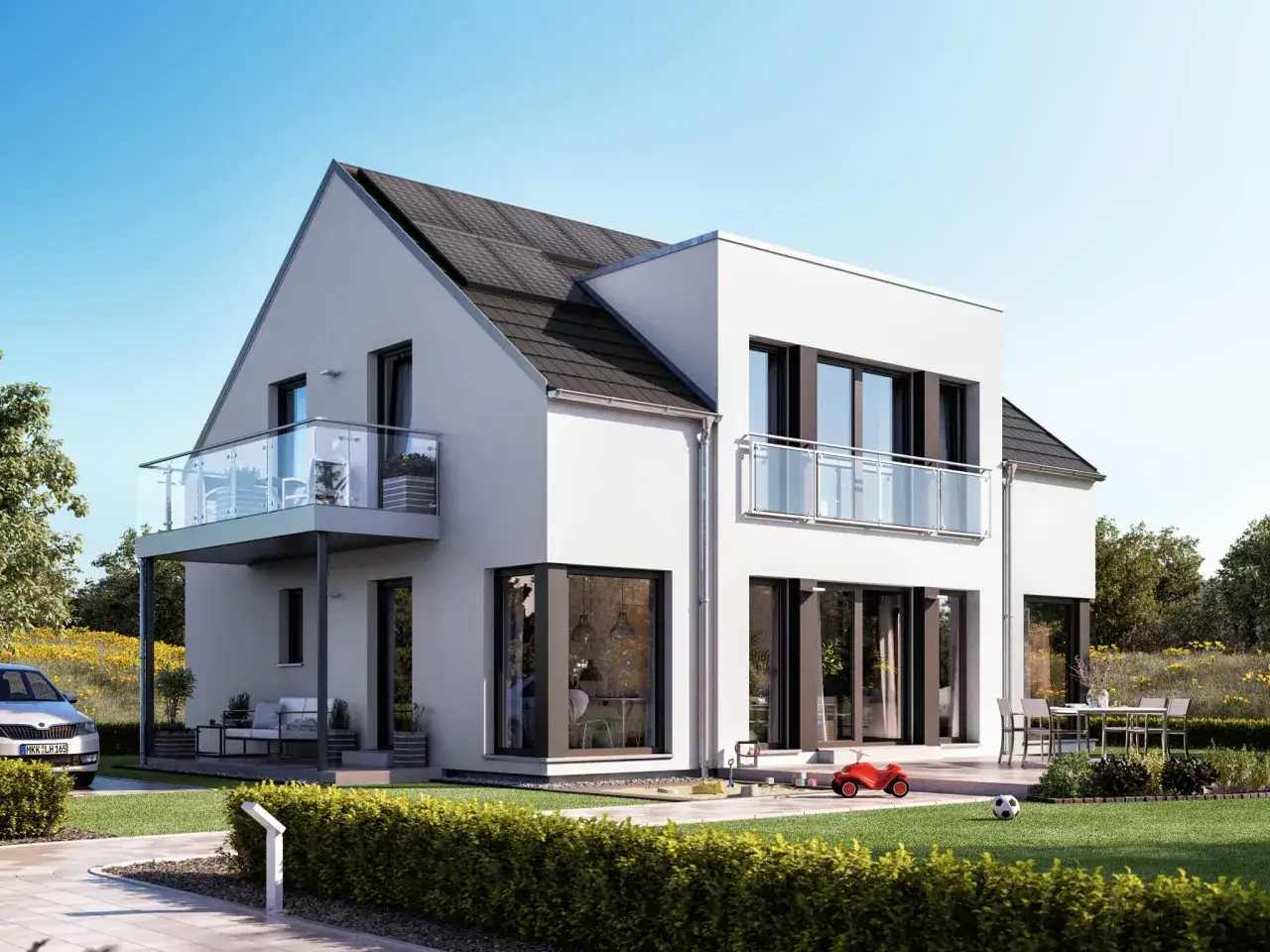 Modernes Haus mit Zwerchgiebel und Satteldach, Solaranlage, Balkon und Gartenm&ouml;beln. Ein Spielzeugauto und Fu&szlig;ball liegen im Rasen.