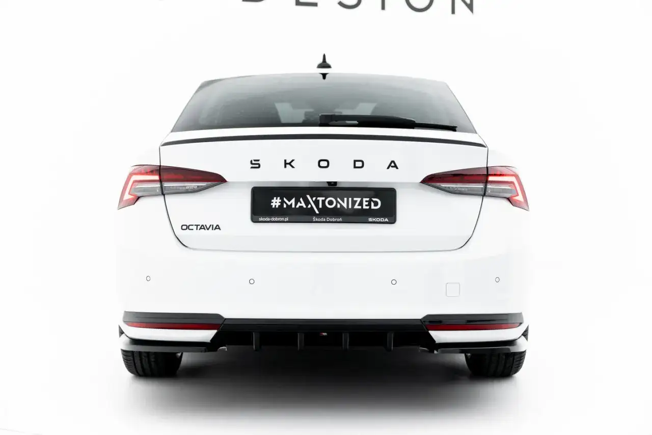 Biała Skoda Octavia sedan z czarnym spoilerem i dyfuzorem. Na klapie bagażnika napis #MAXTONIZED.
