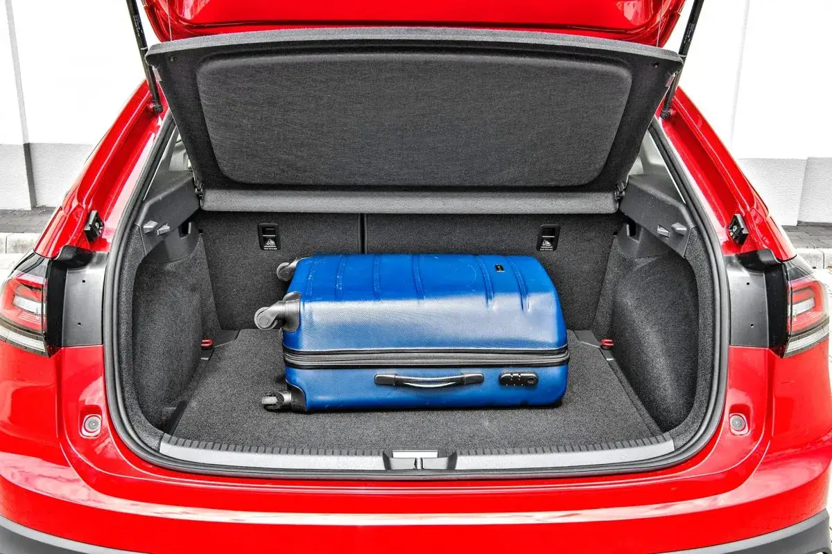 Bagażnik czerwonego VW Taigo gotowy na podróż z niebieską walizką.