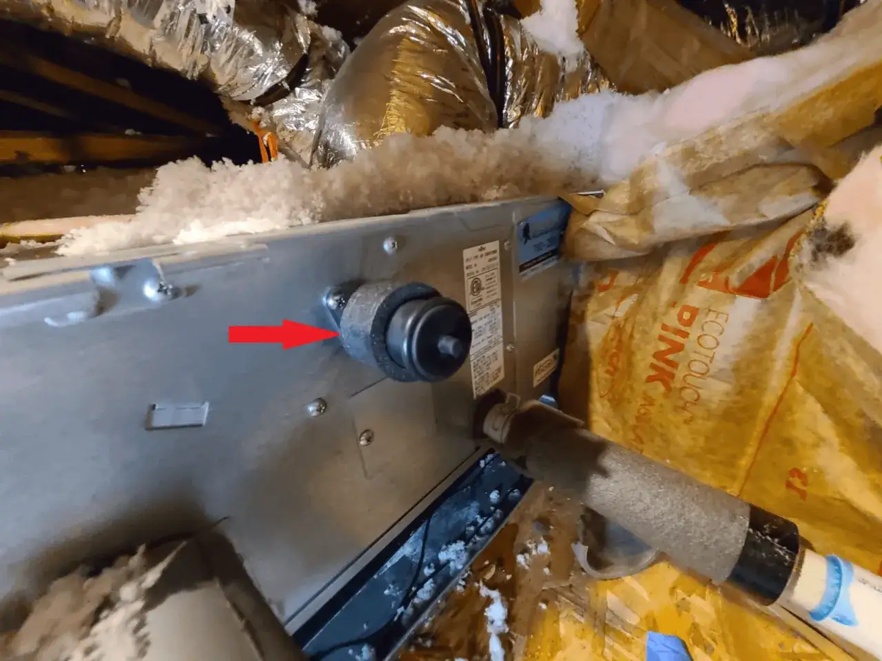 La flecha roja señala una fuga de agua en el sistema de aerotermia, rodeado de aislamiento.