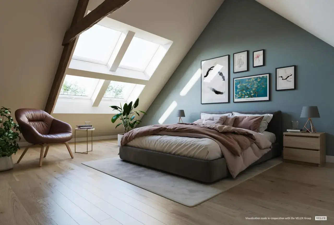 Chambre mansardée : quel mur peindre ? Le mur bleu canard derrière le lit, orné de tableaux, crée une ambiance cosy.