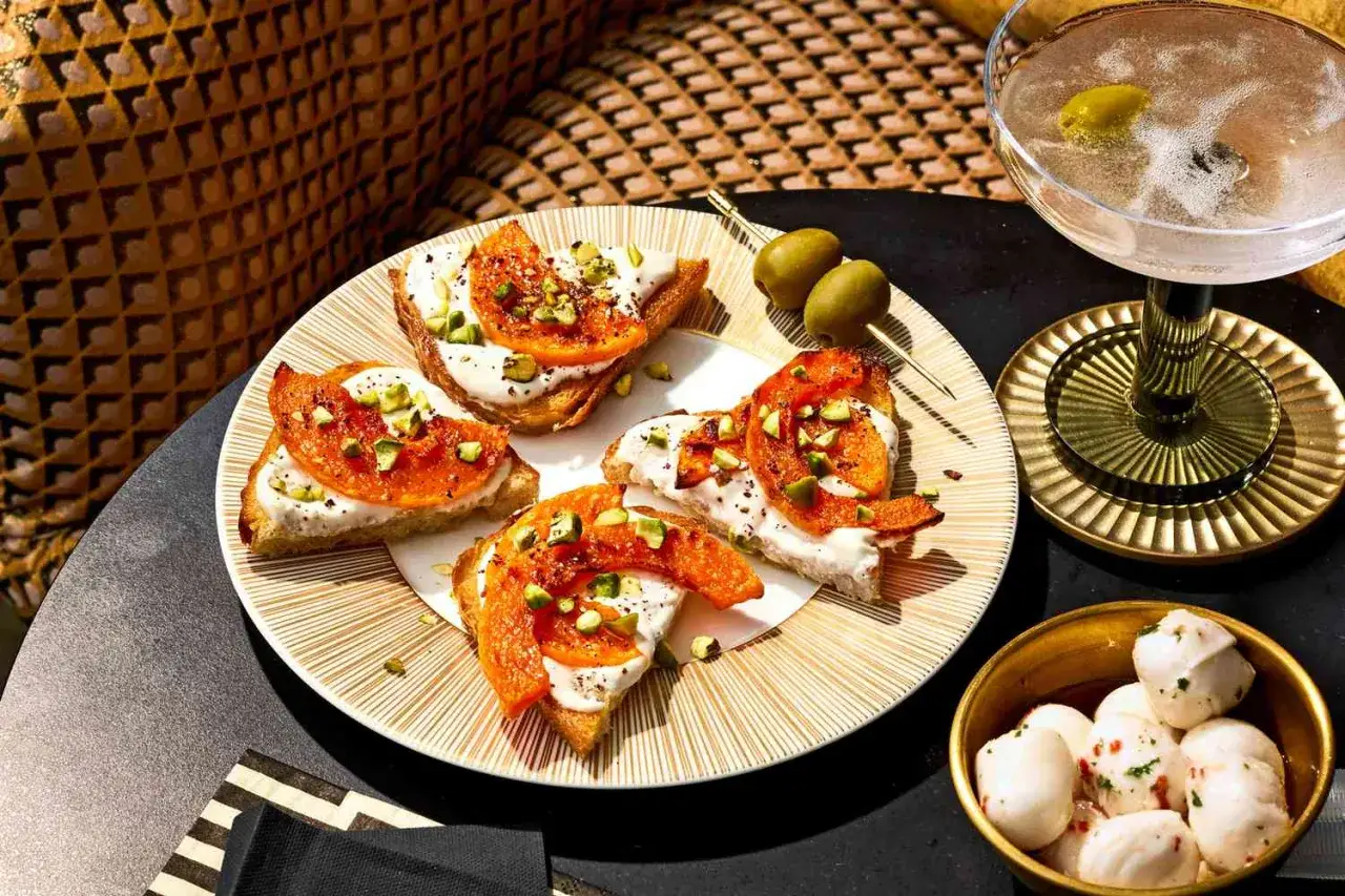 Elegancka obiadokolacja: bruschetty z kremowym serkiem, pomarańczą i pistacjami, oliwki, mini mozzarelle i drink.