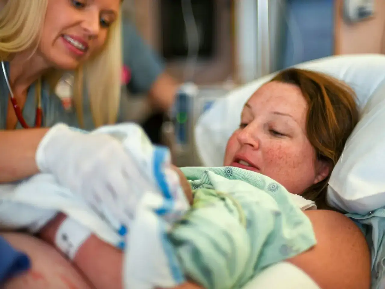 Szczęśliwa mama po narodzinach dziecka, otoczona troską pielęgniarki.
