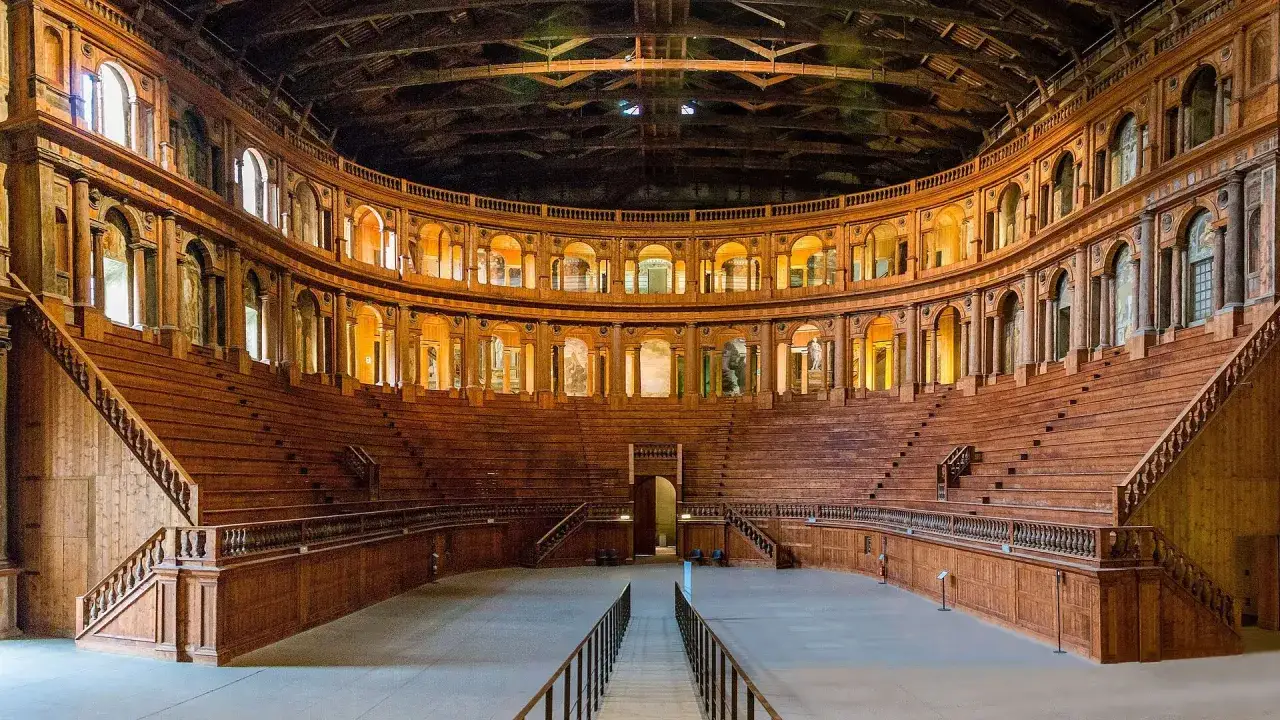 Drewniany, amfiteatralny teatr, niczym theatrum mundi, z rzędami siedzeń i zdobioną fasadą, gotowy na spektakl.