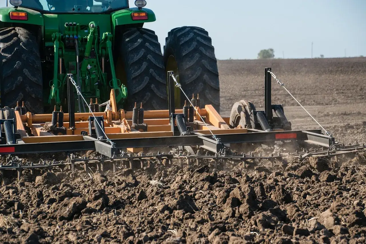 Zielony ciągnik John Deere pracuje na polu, orząc ziemię. Czy to najlepsza marka ciągnika?