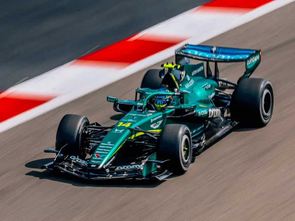 El coche verde de Fernando Alonso 33, número 14, acelera en la pista de carreras, dejando una estela de velocidad.