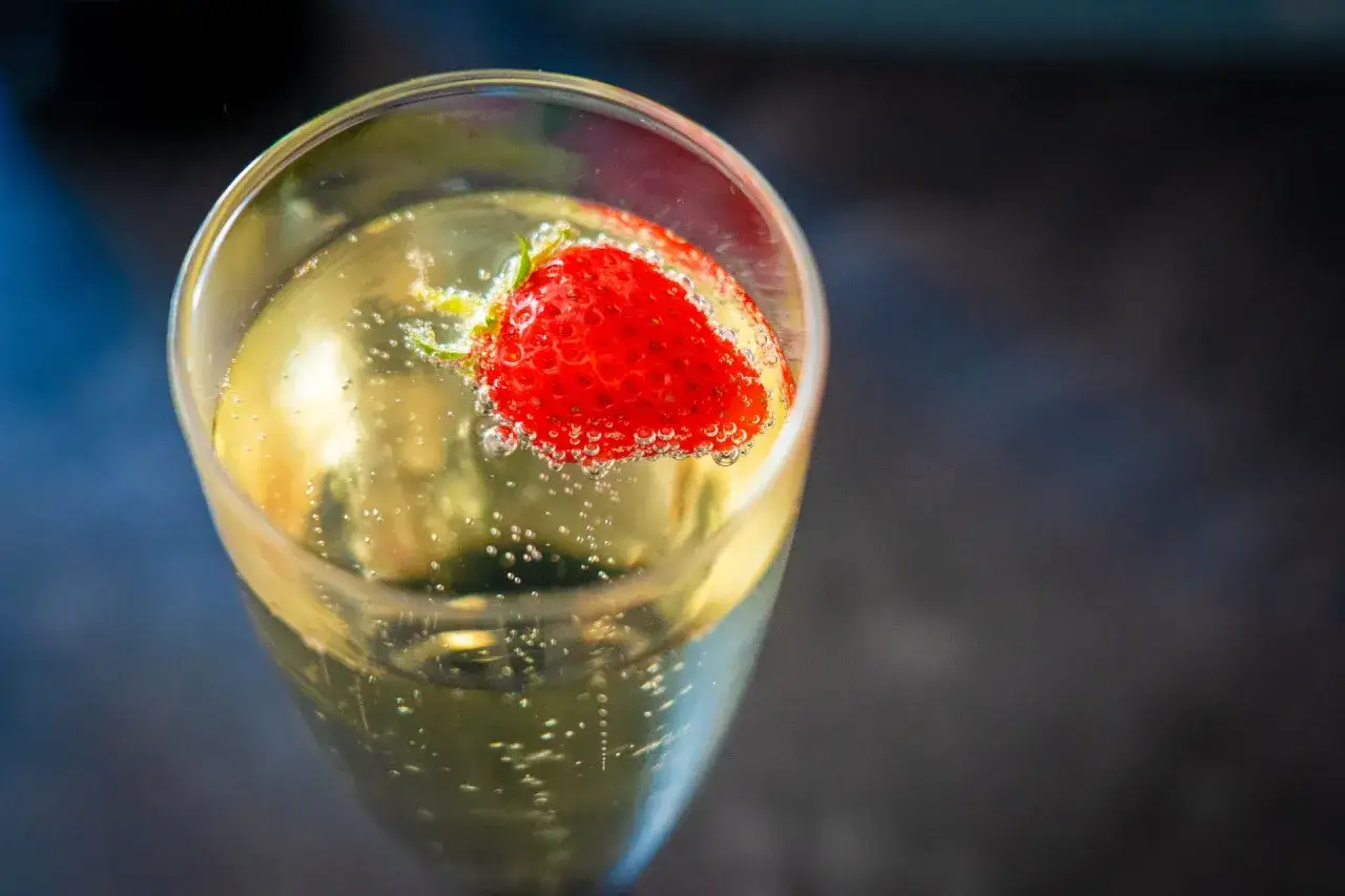 Une coupe de champagne pétillant avec une fraise flottante, évoquant la douceur d'une soupe angevine.