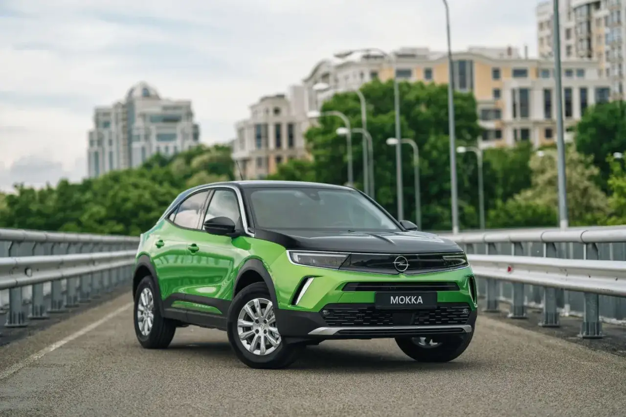 Zielony Opel Mokka na moście, idealny do miasta. Dowiedz się, jak zmniejszyć spalanie auta, wybierając mądre rozwiązania.