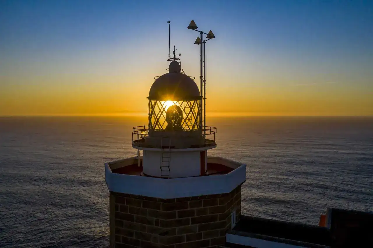 Leuchtturm bei Sonnenuntergang am Kap Finisterre, Spanien. Die Sonne scheint durch das Glas des Turms.