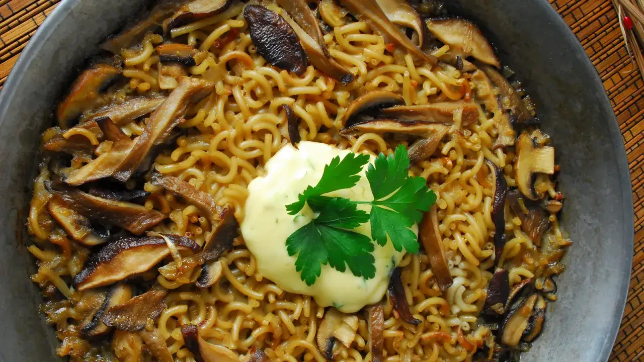 Fideuá de setas con una cucharada de alioli y perejil fresco. Un plato reconfortante y lleno de sabor.