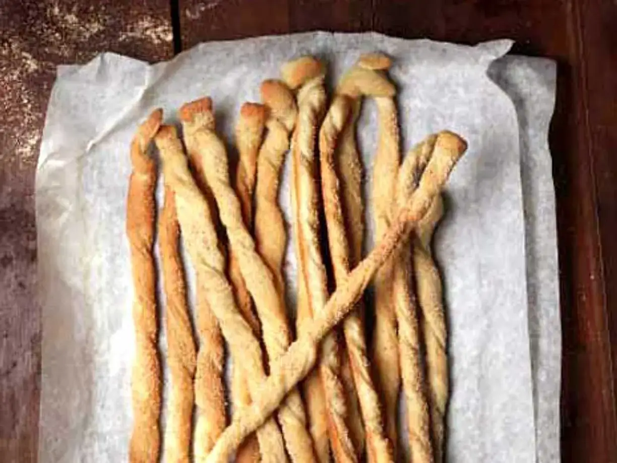 Gyllene, tvinnade grissini p&aring; bakpl&aring;tspapper. Perfekt f&ouml;r ett enkelt grissini recept.