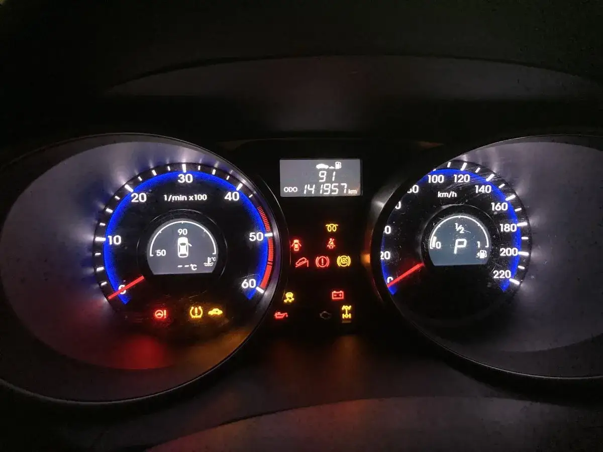 Kontrolka DPF świeci się na desce rozdzielczej Hyundai ix35. Widoczne też inne kontrolki: ABS, ciśnienie w oponach, otwarta klapa bagażnika.