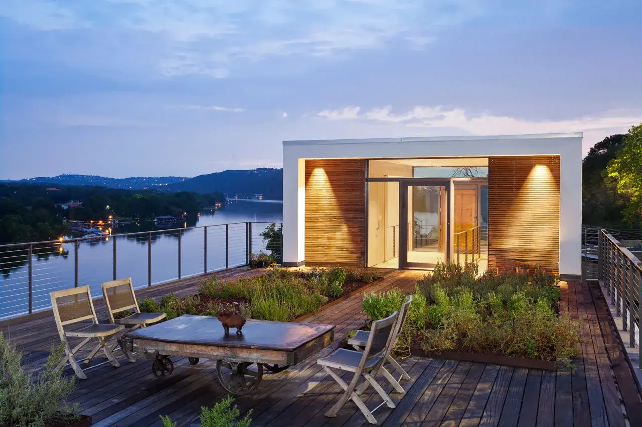 Moderner dachgarten auf einem Flachdach mit Blick auf einen See. Holzdeck, Sitzgelegenheiten und &uuml;ppige Bepflanzung laden zum Entspannen ein.