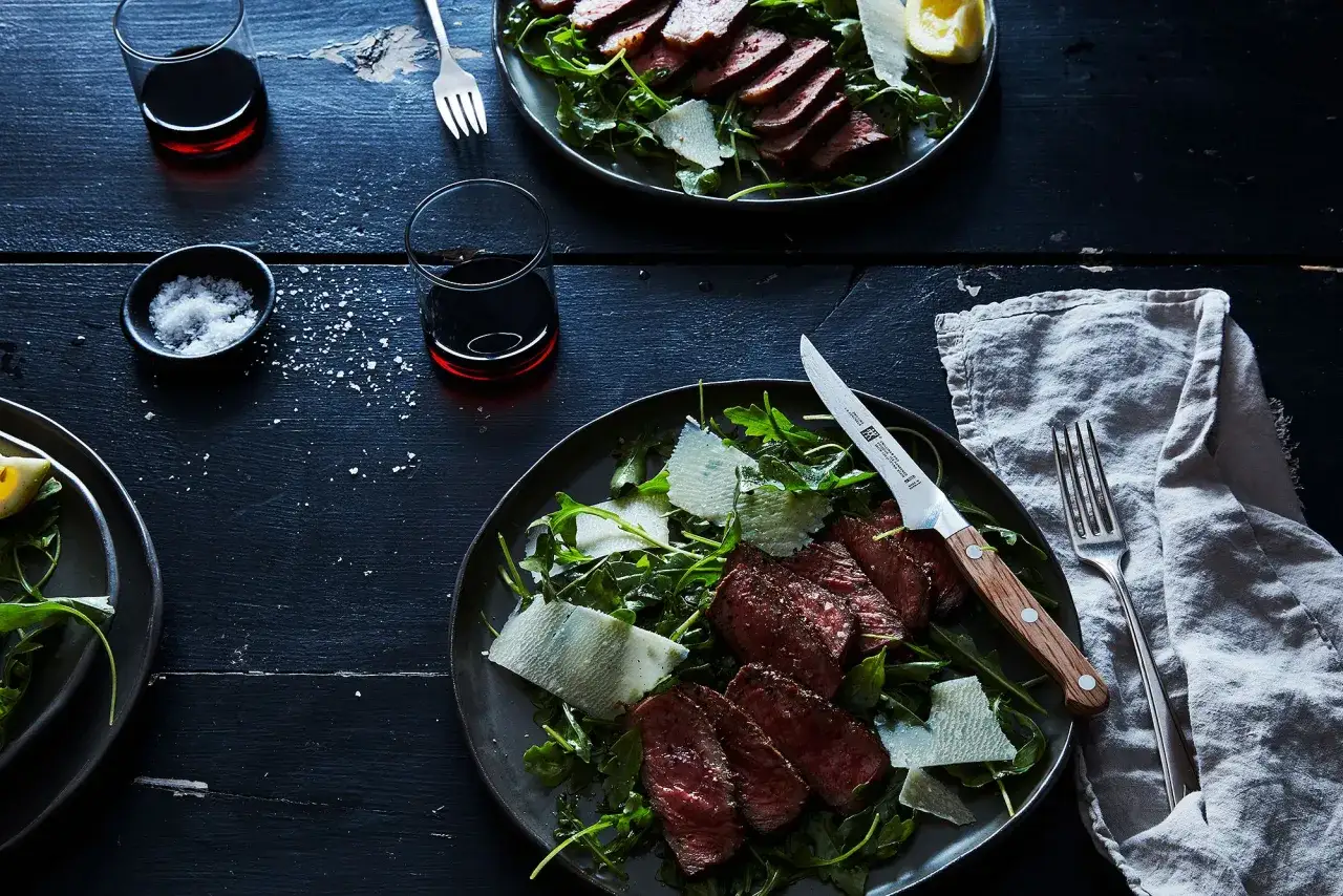 Biff tagliata med rucola och parmesan, serverad med r&ouml;dt vin. En lyxig m&aring;ltid f&ouml;r tv&aring;.